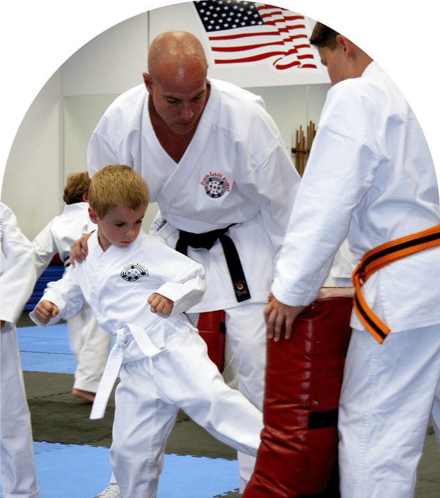 Child practicing karate kick with instructor