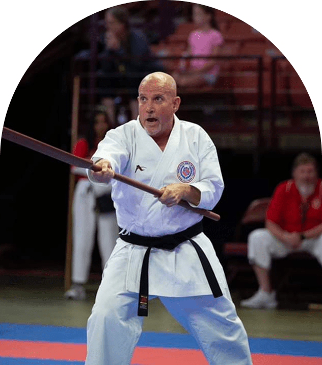 Man in white gi demonstrating bo technique